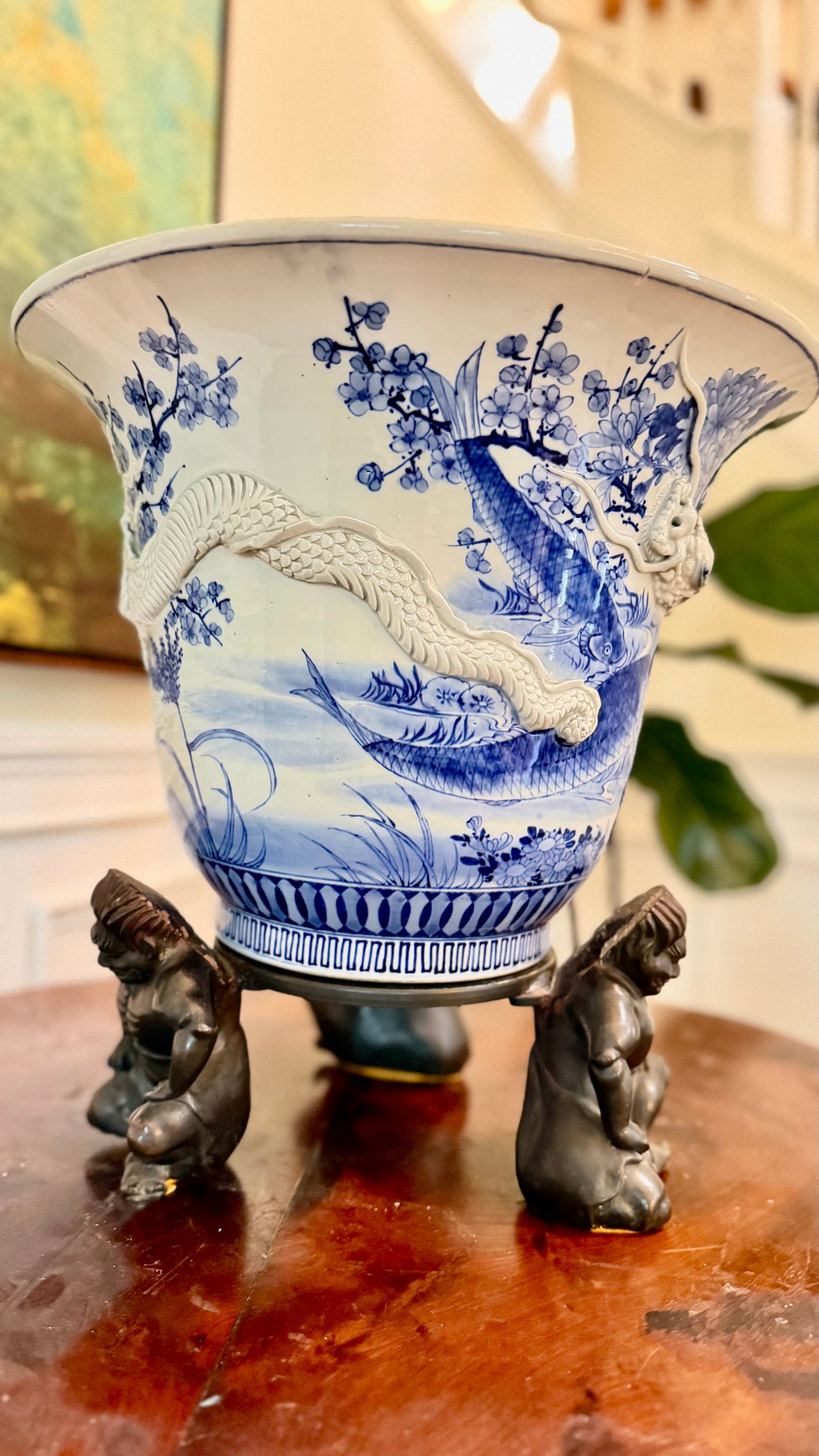 Side view of a Japanese dragon jardinière with koi decoration and bronze figural stand.