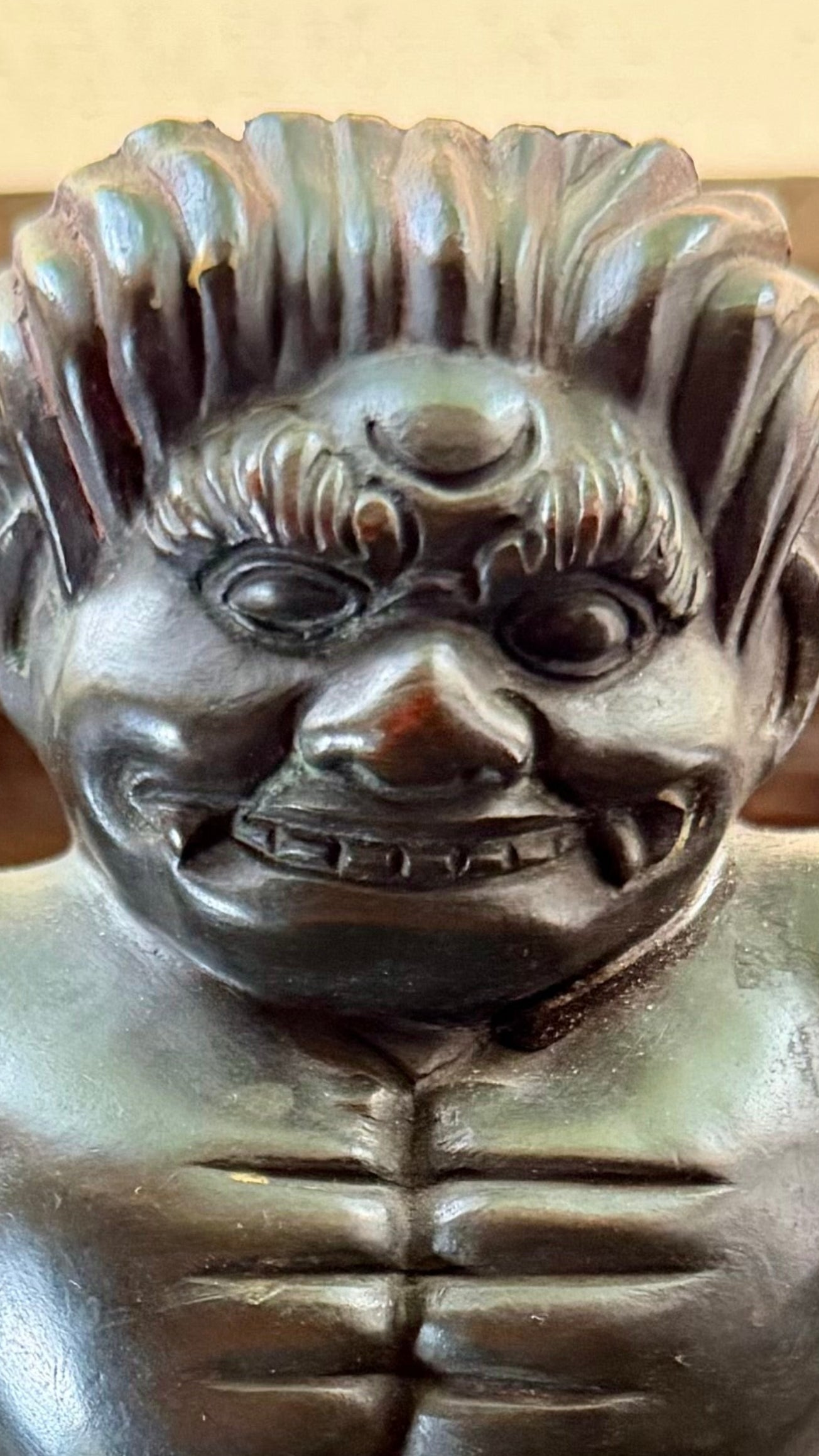 Close-up of a bronze sumo wrestler’s face and swept hair on the Japanese jardinière stand.