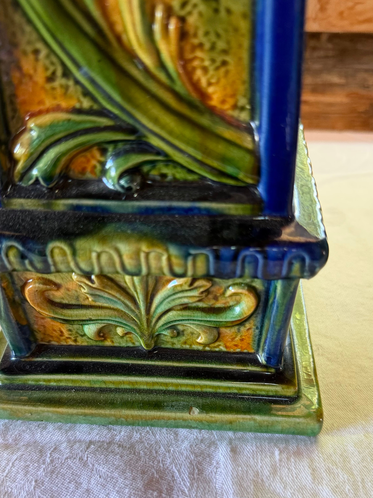 Close-up of raised foliate detail and multicolored glaze on an Italian terracotta obelisk base.