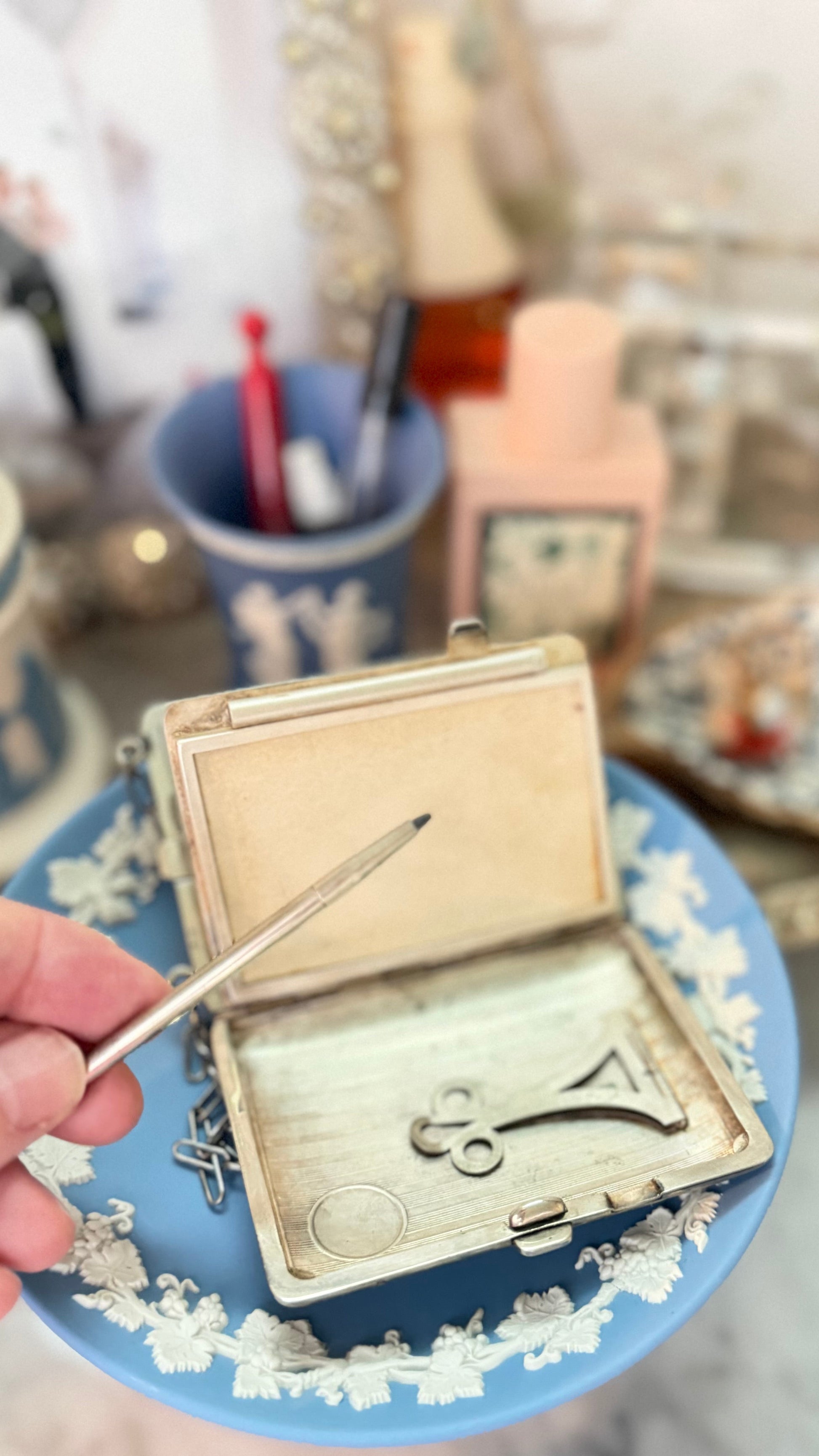 Hand holding the antique dance purse’s original retractable pencil with lead extended above the open writing compartment.